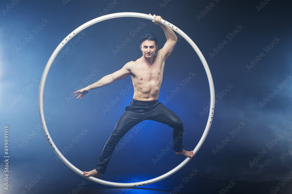  Circus performer artist with muscles body in a Cyr Wheel (Roy Cyr) isolated at  black background
