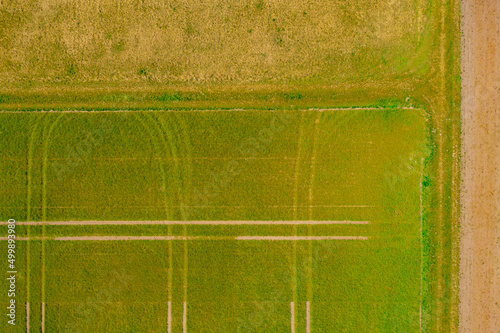 Fields with symmetrical patterns of tractor tracks from drone perspective