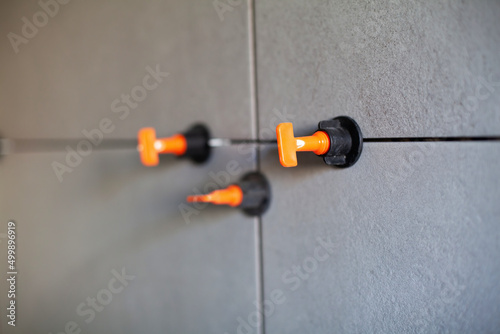Tile leveling system with plastic clips.Tile leveling system. Tiler installing large format tile on wall. tile leveling system