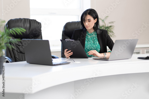 adult businesswoman sitting in the office with documents and laptop © Olga