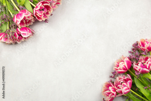 Pink tulips flowers on light gray concrete background. Valentine's, womens, mothers day, easter, birthday or wedding spring holiday flat lay. Top view. Copy space.
