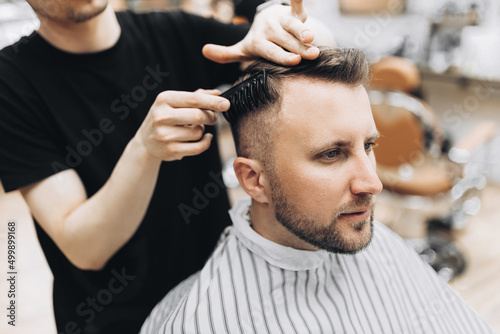 shot of barber styling hair on handsome bearded man