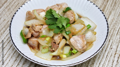 Stir-fried pork with chilli with onions and spring onions served in a white plate, Stir-fried pork with chilli is a popular Thai dish that Thai people eat.