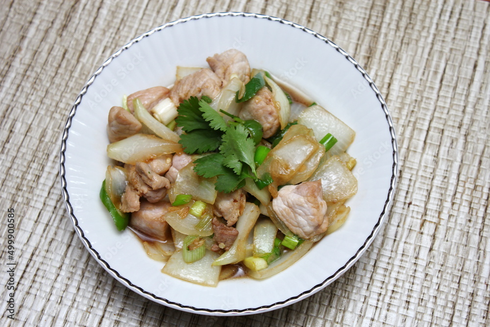 Stir-fried pork with chilli with onions and spring onions served in a white plate, Stir-fried pork with chilli is a popular Thai dish that Thai people eat.