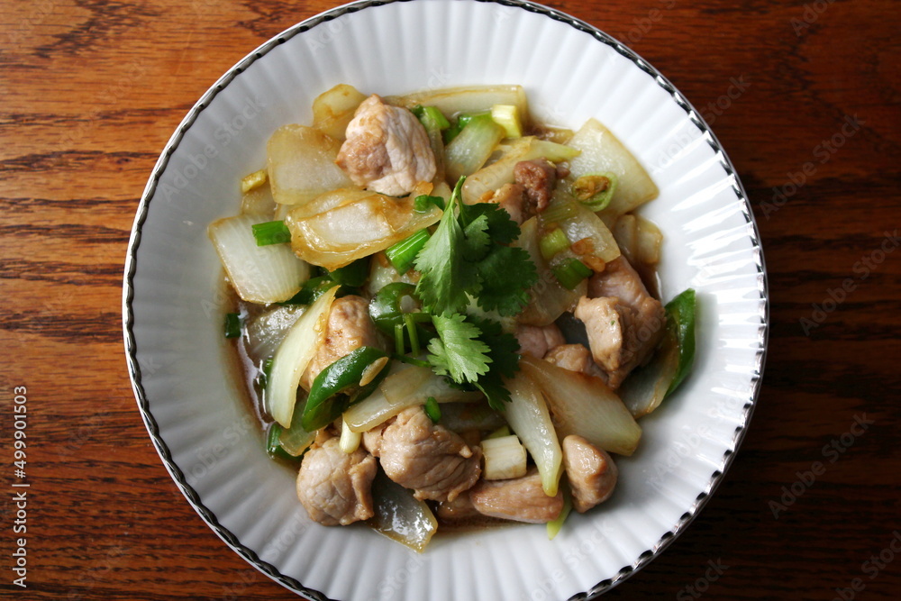 Stir-fried pork with chilli with onions and spring onions served in a white plate, Stir-fried pork with chilli is a popular Thai dish that Thai people eat. Stir-fried pork with chilli with onions and spring onions served in a white plate, Stir-fried pork with chilli is a popular Thai dish that Thai people eat.