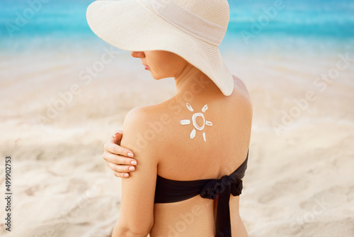 Beautiful woman in bikini applying sun cream on tanned  shoulder. sun protection. Skin and body care. Girl using sunscreen to skin