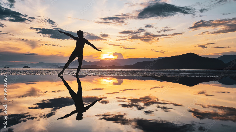 Silhueta de um homem se exercitando na beira da praia durante pôr do sol