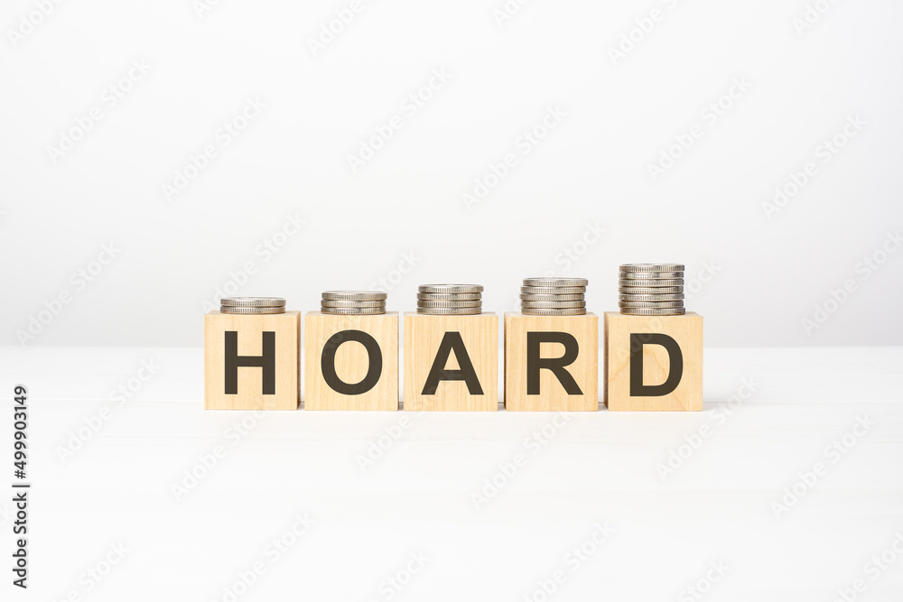 Obraz premium HOARD text written on wooden block with stacked coins on white background