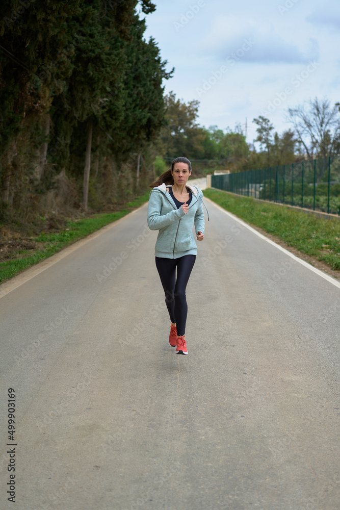 woman running on the road in the forest front view