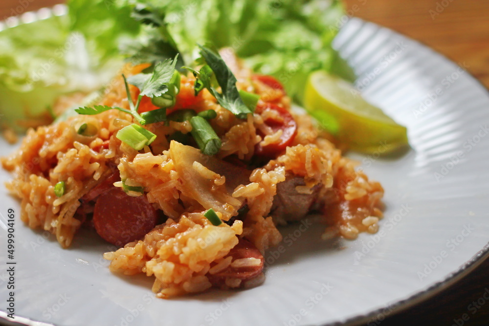 Pork and sausage fried rice served in a plate with lettuce and coriander garnish. Fried rice is a street food that is sold in Thailand. Pork and sausage fried rice served in a plate with lettuce and coriander garnish. Fried rice is a street food that is sold in Thailand.