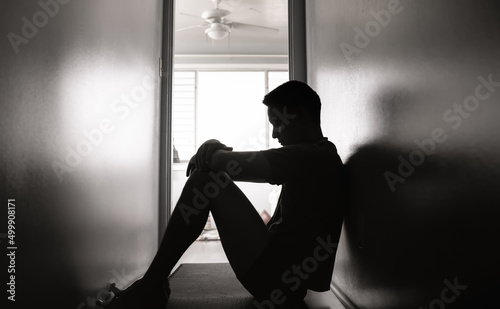 Silhouette of sad and depressed man sitting in a dark room  photo