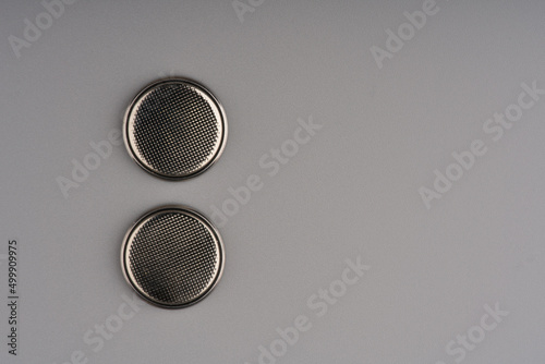 Two round flat batteries commonly used for TV remote controls on a gray background. Lots of space for text photo