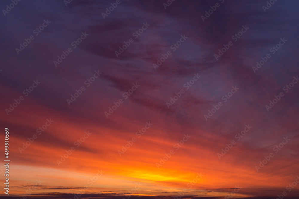 Epic dramatic sunrise, sunset orange red pink clouds in sunlight on dark blue sky background texture	