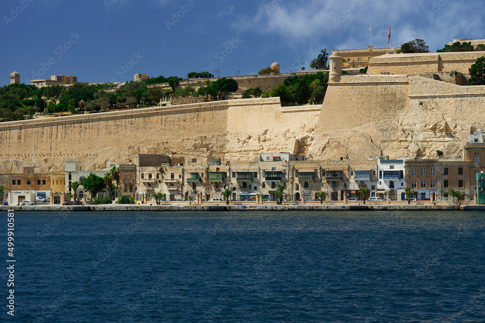 Valletta, Malta day view of traditional waterfront houses on The Grand Harbour, below Upper Barrakka Gardens with fortifications, UNESCO World Heritage Site.