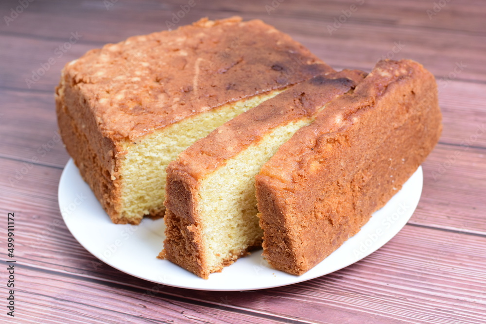 Homemade vanilla cake, displayed on plate and wooden background Homemade vanilla cake, displayed on plate and wooden background
