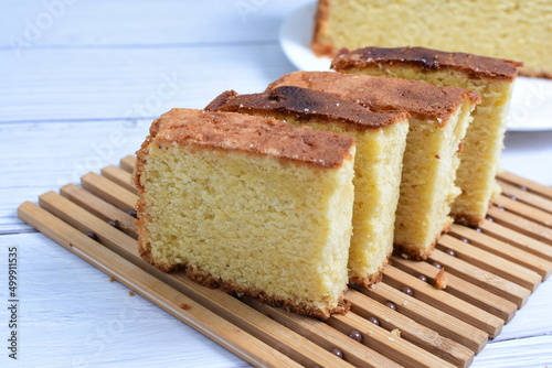 Homemade vanilla cake  displayed on a plate and portioned and on a wooden background
