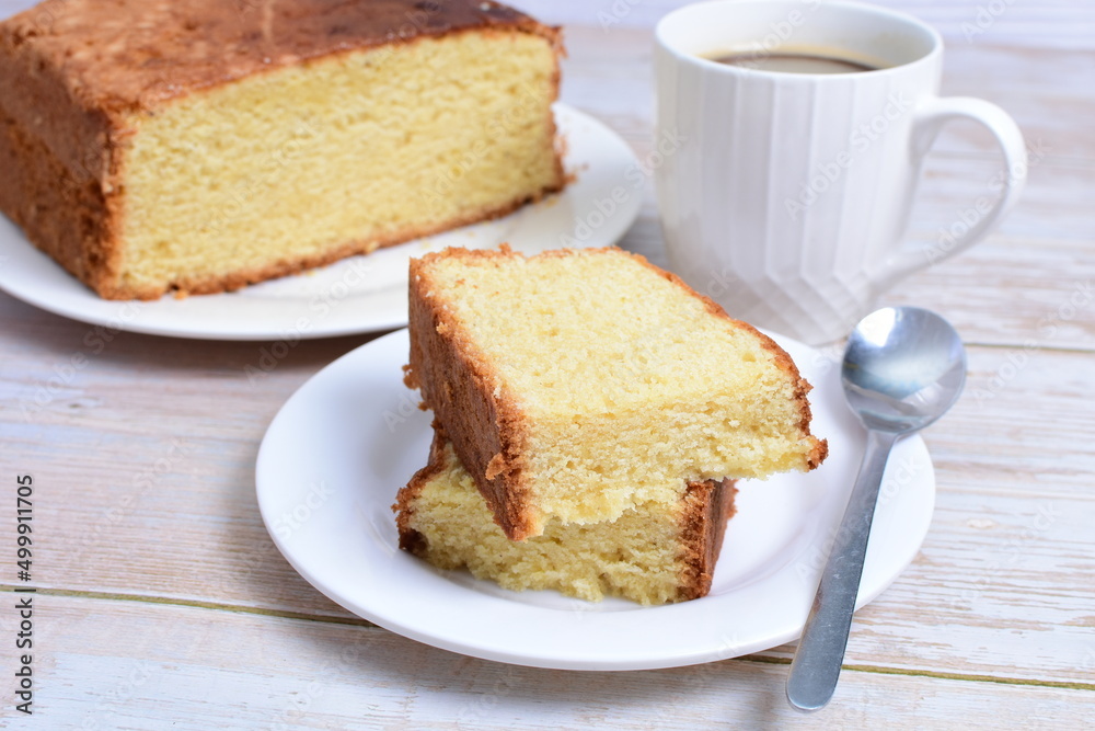 Homemade vanilla cake, displayed portioned and traces of coffee in the background on wood Homemade vanilla cake, displayed portioned and traces of coffee in the background on wood