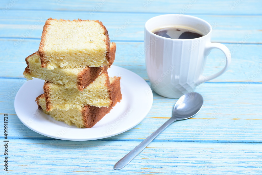 Homemade vanilla cake, displayed portioned and traces of coffee in the background on wood Homemade vanilla cake, displayed portioned and traces of coffee in the background on wood