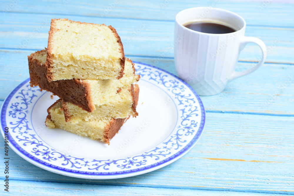 Homemade vanilla cake, displayed portioned and traces of coffee in the background on wood Homemade vanilla cake, displayed portioned and traces of coffee in the background on wood