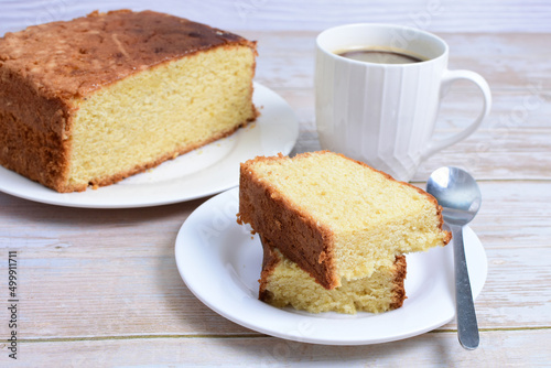 Homemade vanilla cake, displayed portioned and traces of coffee in the background on wood