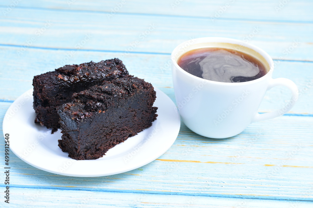 Traditional black ponque, with raisins, red wine flavor accompanied by a cup of coffee on a wooden background Traditional black ponque, with raisins, red wine flavor accompanied by a cup of coffee on a wooden background
