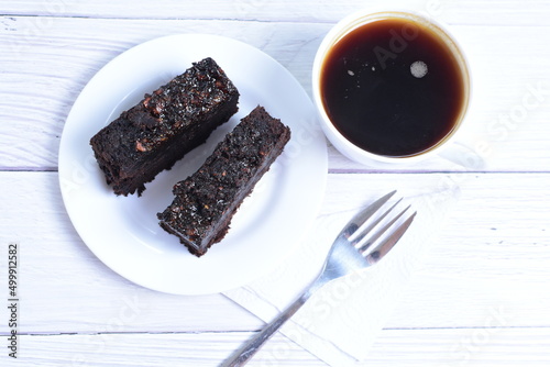 Traditional black ponque, with raisins, red wine flavor accompanied by a cup of coffee on a wooden background