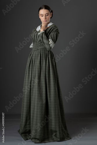Fototapet A Victorian working class woman wearing a checked bodice and skirt and standing