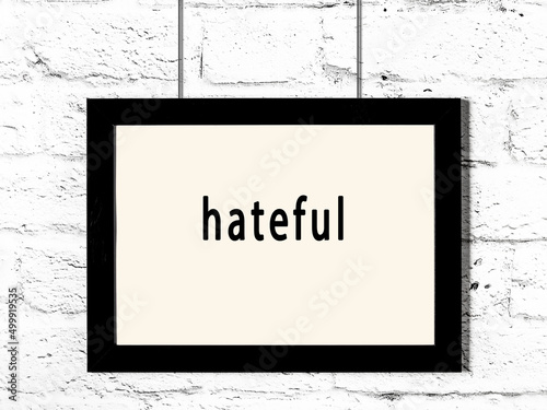 Tablou pe pânză Black frame hanging on white brick wall with inscription hateful