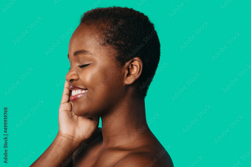 Side view of a smiling african woman enjoying her silky facial skin isolated over navy blue background. Beauty face. Facial skincare. Hair care. Beautiful black Side view of a smiling african woman enjoying her silky facial skin isolated over navy blue background. Beauty face. Facial skincare. Hair care. Beautiful black