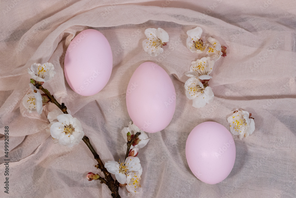 Happy Easter. Easter eggs on a delicate pink background with flowers.Minimalistic style,top view,flat.