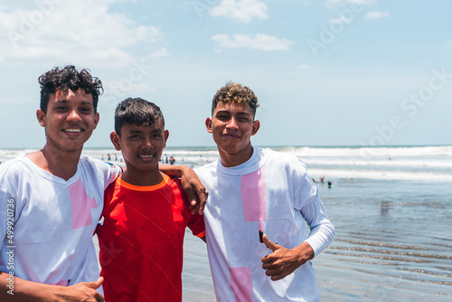 Group of young Latinos in soccer uniforms posing in front of the camera on the beach. Concept of sports in the summer. photo