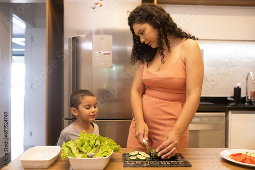 Mãe falando com filho na cozinha preparando salada photo