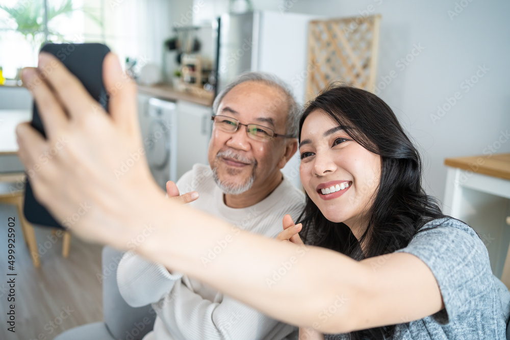 Obraz premium Asian lovely family, young daughter use phone selfie with older father