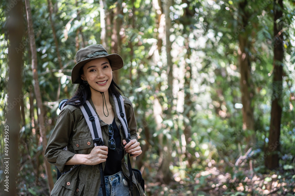 Portrait of Asian beautiful woman backpacker traveling alone in forest