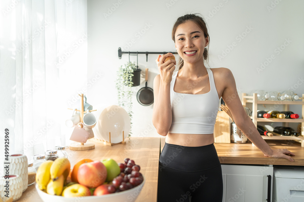 Portrait of Asian attractive woman hold red apple in kitchen at home. 