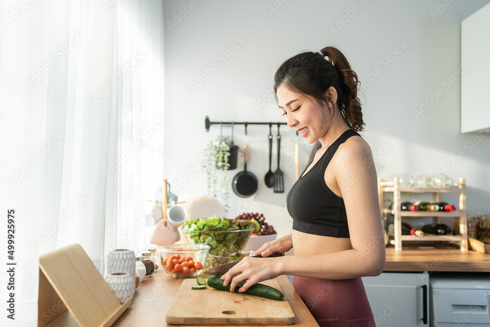 Asaian attractive woman wear sport clothes cook green salad in kitchen Asaian attractive woman wear sport clothes cook green salad in kitchen