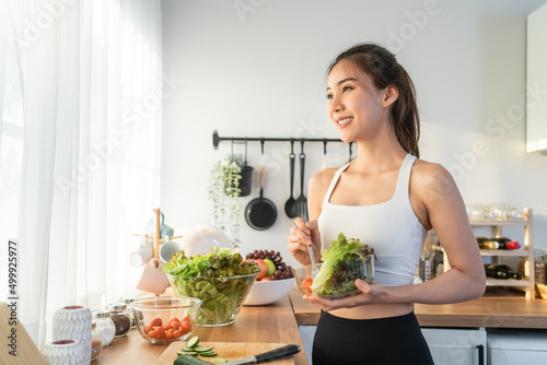 Asian attractive sport woman holding salad bowl and eat vegetables.