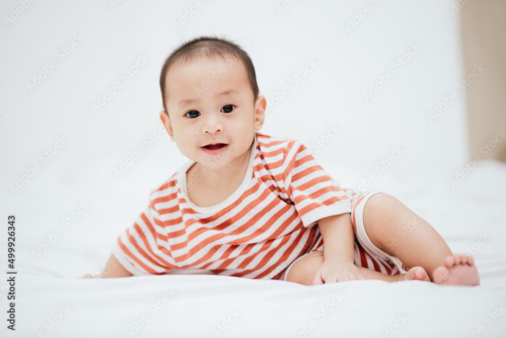 Cute happy baby boy smiling and playing with toys on the bed. Infant child relaxing. Adorable baby. Healthy baby. Cute happy baby boy smiling and playing with toys on the bed. Infant child relaxing. Adorable baby. Healthy baby.