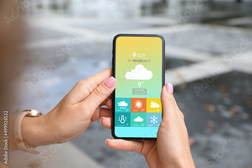 Young woman using weather forecast app in her mobile phone, closeup