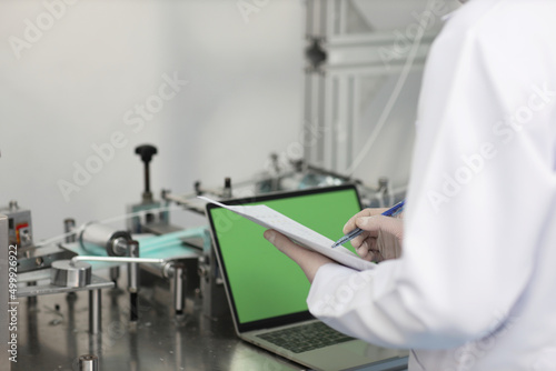 Inspector man or worker male hands doing quality of mask and medical face mask production line with blank green screen computer, Industry and factory concept.