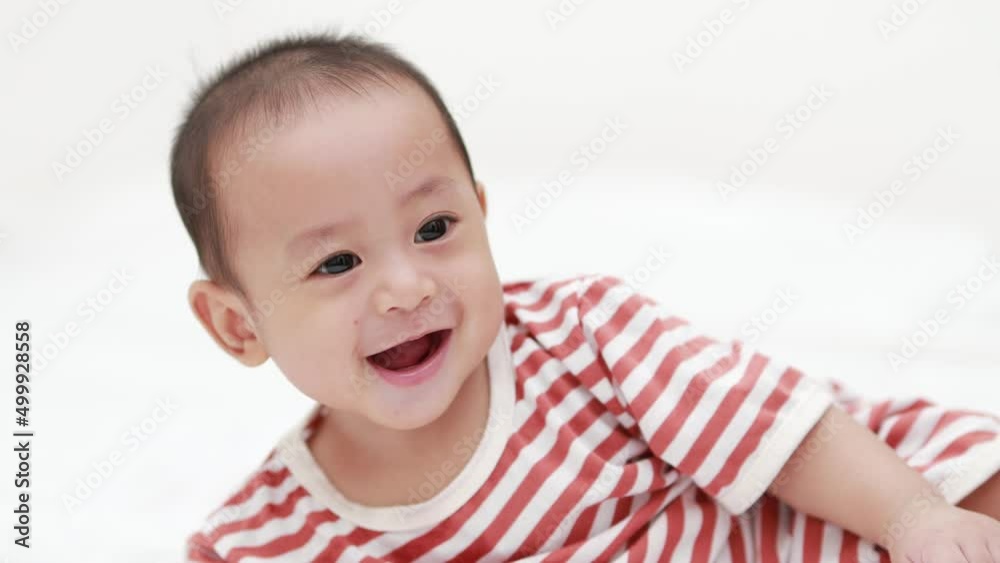 Cute happy baby boy smiling and playing with toys on the bed. Infant child relaxing. Adorable baby. Healthy baby. Cute happy baby boy smiling and playing with toys on the bed. Infant child relaxing. Adorable baby. Healthy baby.