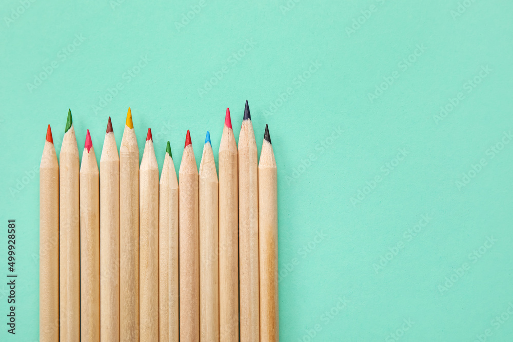 Obraz premium Row of sharpened wooden colored pencils with various lead colors on a mint green background education and creativity, this composition education creativity and artistic expression