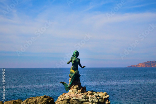 estatua de sirena sobre unas rocas con un mar azul en el fondo y un cielo con nubes en mazatlan sinaloa  photo