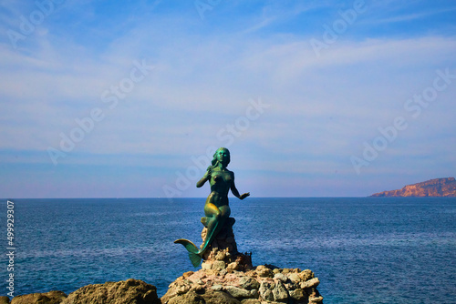 estatua de sirena sobre unas rocas con un mar azul en el fondo y un cielo con nubes en mazatlan sinaloa 