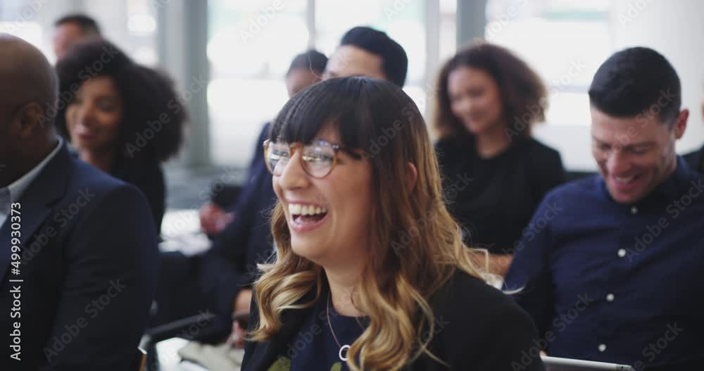Group of young diverse business people sitting in a conference room laughing while listening to a work presentation. Happy colleagues having fun and enjoying learning seminar in a training workshop