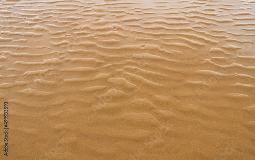 Detail of sand with water and small dunes on the beach 