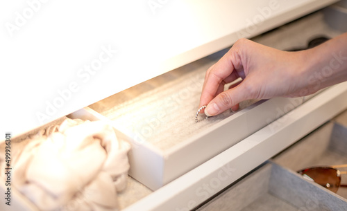 Female hand choosing the ring from the jewelry box that is decorated in the built-in wardrobeobe in the bedroom,
