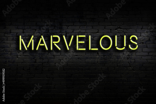 Neon sign. Word marvelous against brick wall. Night view