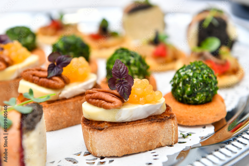 Catering. Colorful meat snacks with bread fruits and vegetables on a white plate.