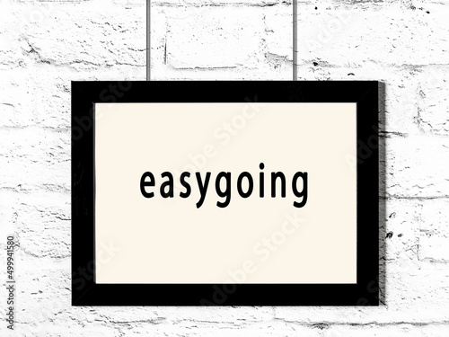 Fényképezés Black frame hanging on white brick wall with inscription easygoing